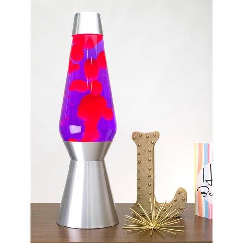 27” LAVA® Lamp Grande – Pink/Purple/Silver on a table with knick knacks
