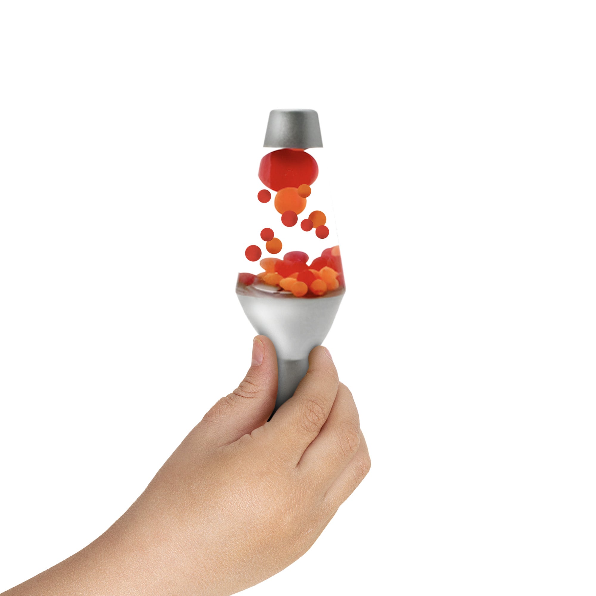 A hand holding a small, squishy silver Motion Lamp toy. Red and orange globs float upward from the base, giving the illusion of the lamp's typical flowing motion against a plain white background.